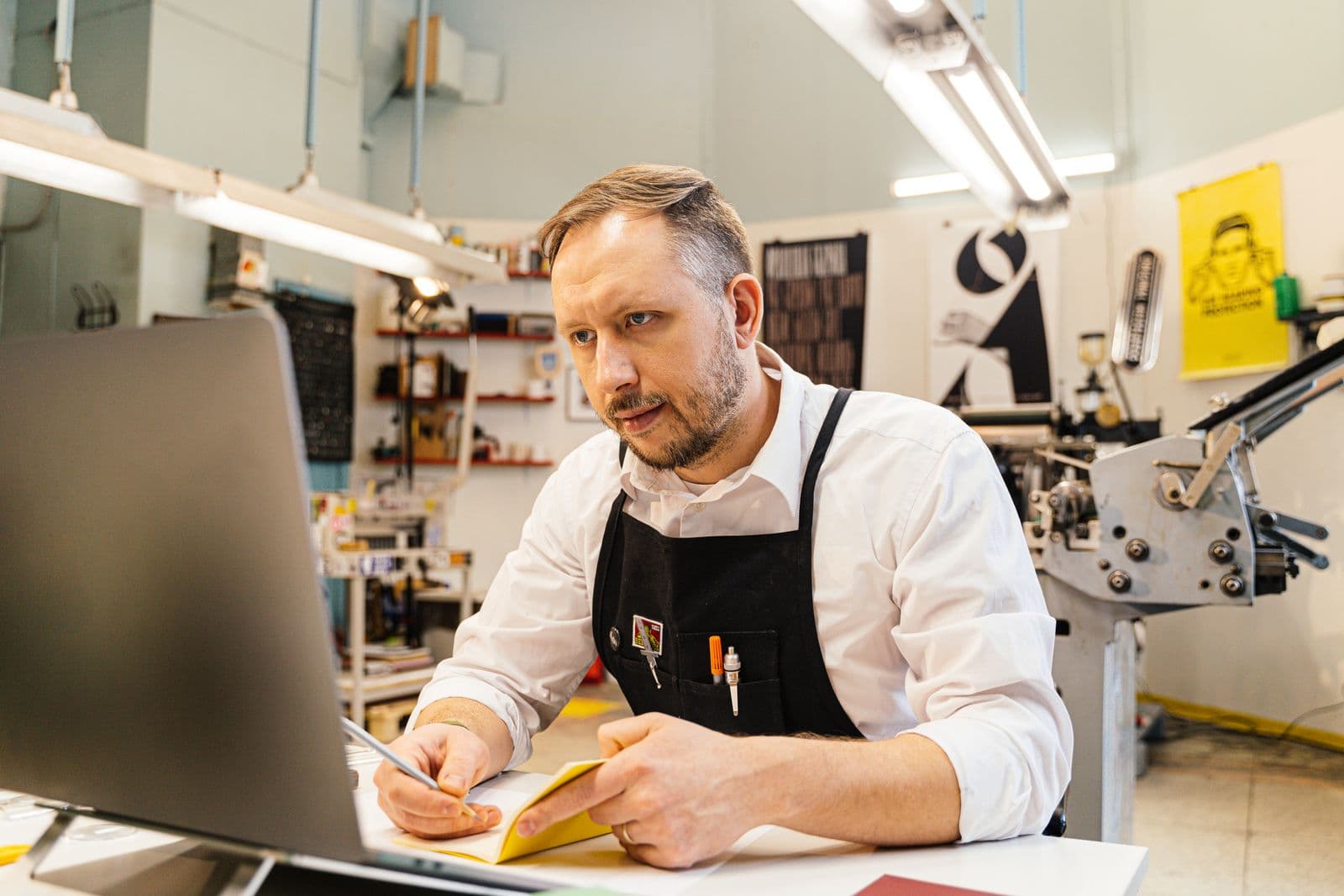 A shop owner working at a computer in a busy print shop.